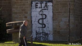 Человек смотрит на лозунг группировки ЭТА, написанный на стене