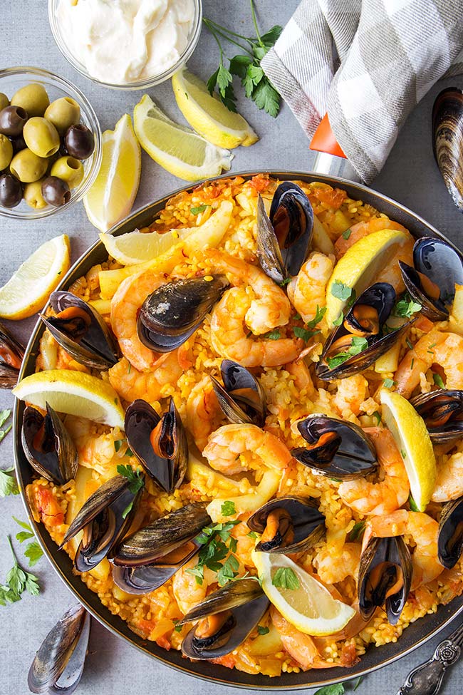 This Spanish Seafood Paella features a crusty saffron and veggie infused layer of rice topped with squid, mussels, and shrimp. The best seafood dish ever! 