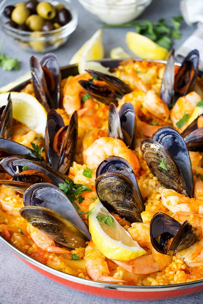 This Spanish Seafood Paella features a crusty saffron and veggie infused layer of rice topped with squid, mussels, and shrimp. The best seafood dish ever! 